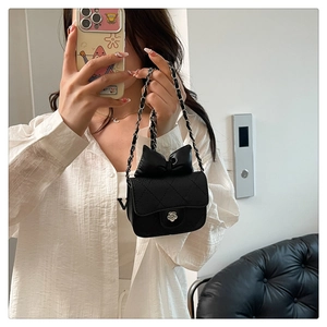 Close-up of black quilted leather mini bag featuring a silver camellia clasp and bow