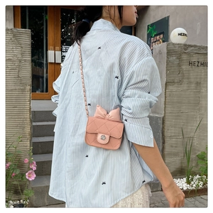 Detail of pink mini quilted crossbody bag featuring a large bow and floral metal clasp