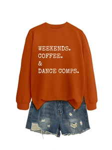 Flat lay of an orange sweatshirt with white typography print and distressed denim shorts