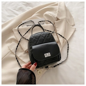 Detail of black quilted leather backpack with silver turn-lock and chain strap