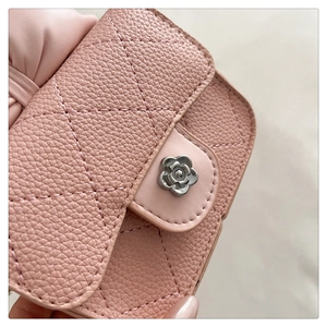 Close-up of pink quilted leather bag featuring a silver camellia buckle and bow detail