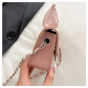 Detail of pink mini quilted crossbody bag with bow decoration and leather chain strap
