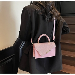 Pink rhinestone handbag detail featuring a woven handle and shiny glitter flap design