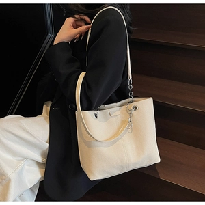 Detail of off-white canvas tote bag with textured fabric and metallic chain strap