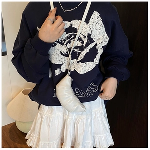 Detail of a white crossbody dumpling bag paired with a navy rose graphic sweatshirt