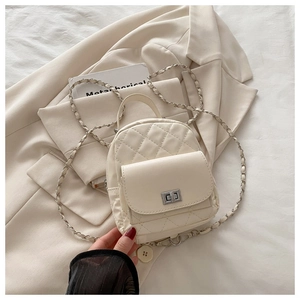 Detail of cream quilted mini backpack with silver turn-lock and woven chain strap