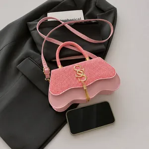 Detail of pink leather handbag with gold S-buckle, woven flap and wavy bottom design