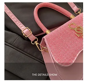Detail of pink saddle bag featuring gold metal hardware and fabric woven flap texture