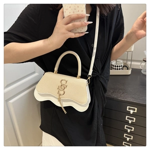 Detail of beige straw crossbody bag featuring wavy edge design and gold metal S logo