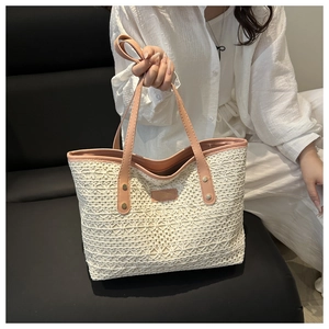 Detail of hollow woven tote bag featuring pink leather handles and metal rivets