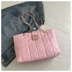 Macro detail of pink quilted tote bag with golden metal buckle and chain strap