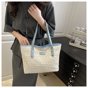 Detail of knit tote bag featuring light blue leather handles and chic metallic logo plaque