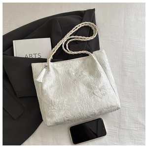 Détail du sac cabas en dentelle blanche avec broderie florale et bandoulière tressée