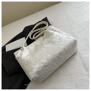 Détail de la broderie papillon blanche sur le sac avec pompon et bandoulière tissée