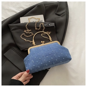 Dettaglio della borsa vintage in denim blu con texture 3D e tracolla a catena d'oro