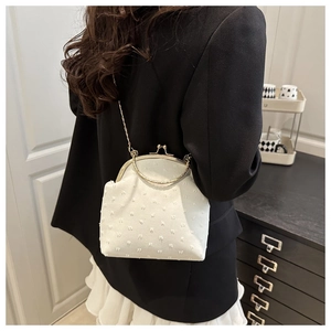 Vista detallada del bolso de concha blanco con asa dorada y jacquard en modelo