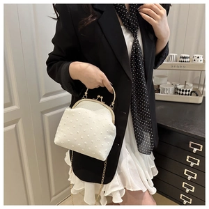 Detalle de bolso de noche jacquard blanco con asa de anillo dorada y correa de cadena