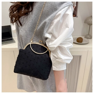 Retro black polka dot shell bag with gold handle and chain strap shown on a table