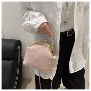 Dettaglio della borsa ricamata rosa con manico dorato e tracolla a catena rimovibile