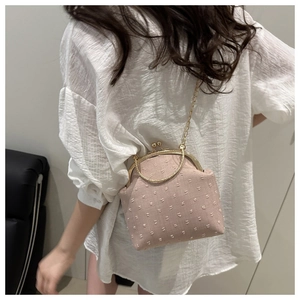 Détail d'un sac à chaîne rose sur chemise blanche montrant la taille et le style du sac