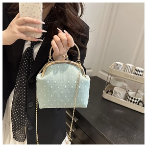 Close-up of mint green shell bag featuring embossed dot texture and golden ball clasp