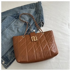Detailed view of brown quilted leather tote bag with gold logo lock and chain strap