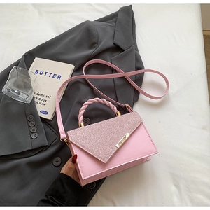 Detail of pink fashion handbag featuring glitter flap and woven handle on textile