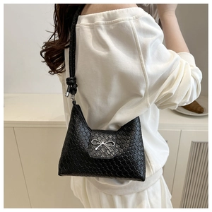 Détail du sac croissant tissé noir avec un nœud en métal argenté et une bandoulière nouée