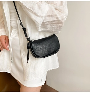 Détail du sac à bandoulière en cuir grainé noir avec lanière nouée et finitions argentées