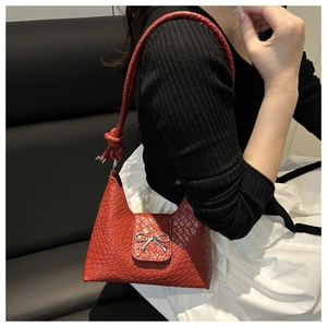 Close-up of deep red woven shoulder bag featuring a silver metallic bow buckle detail