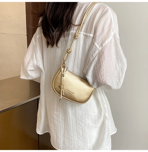 Detailansicht der champagner-goldenen Halbmond-Tasche mit genarbtem Leder und Knoten