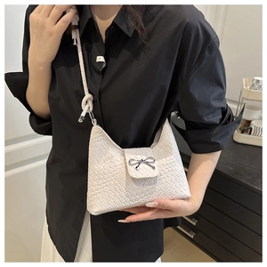 Détail du sac bandoulière blanc tressé avec nœud argenté et bandoulière tressée chic