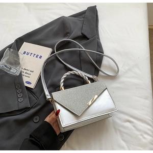 Detail of silver crossbody bag featuring glitter flap and twisted metallic handle