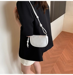 Macro shot of white lychee leather dumpling bag with textured knotted shoulder strap details