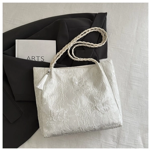 Close-up of white lace tote bag with detailed floral embroidery and butterfly patterns