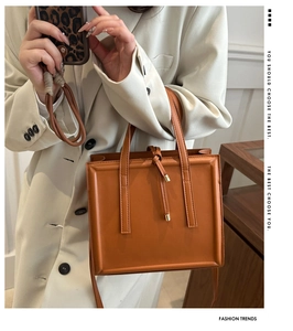 Detail of caramel brown PU leather handbag featuring elegant knot handle and square frame