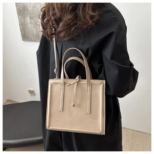 Detail of glossy beige leather shoulder bag with drawstring and golden hardware accents