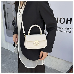 Chic beige crossbody bag with gold metal clasp on a model in a black blazer