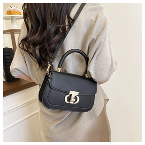 Detailed view of black crossbody bag with gold logo buckle and adjustable strap