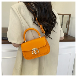 Detail of a bright orange crossbody bag with a modern silver swivel lock and handle