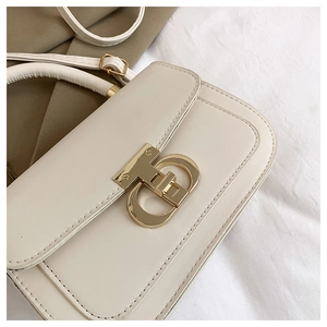 Gros plan d'un sac en cuir crème avec fermoir à logo en métal doré décoratif