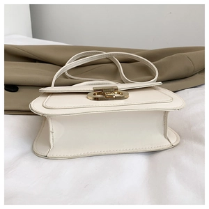 Détail du sac à rabat crème avec boucle en métal doré et bandoulière assortie élégante