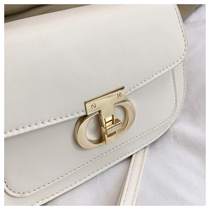 Gros plan du sac en cuir beige avec fermoir en métal doré poli et coutures fines