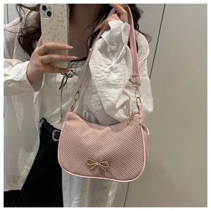 Detail of pink fabric shoulder bag with golden metal bow and zipper closure