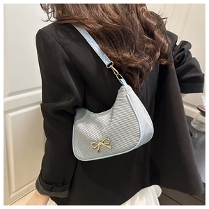 Close-up of light blue woven texture and gold bow detail on French style hobo bag