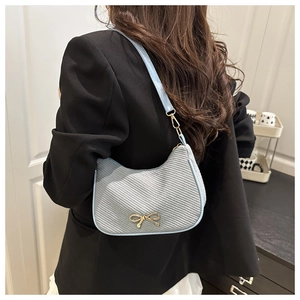 Close-up of light blue underarm bag with gold bow detail worn by a model