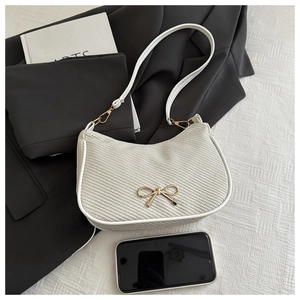 Detail of cream woven shoulder bag with gold bow buckle and elegant white leather trim