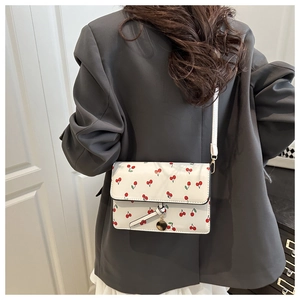 Détail du mini sac à bandoulière blanc avec imprimé cerise et fermoir en métal doré