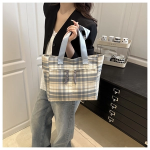 Détail du sac cabas en toile à carreaux avec pompons bleus et poche frontale