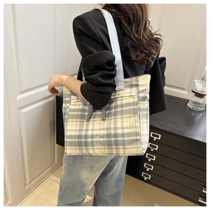 Close-up of a blue and yellow plaid canvas tote bag showing side pocket and woven handles
